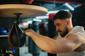 A young man is training with a speed bag in a boxing gym