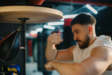 A young man is training with a speed bag in a boxing gym