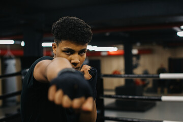 A strong young boxer trains his punches in the gym.