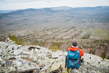 A traveler with a backpack enjoys the view from a rocky mountain top
