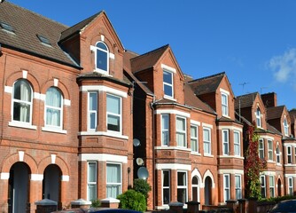typical English small town street with narrow terraced, adjoining red brick houses with bay windows