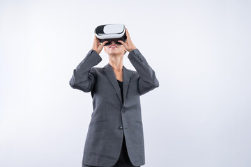 Skilled businesswoman looking at visual reality world by using VR glass while standing at...