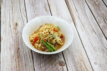 Papaya salad in a white bowl on a wooden table