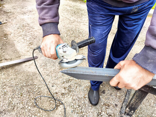 Craftsman Cutting Metal Column With Grinder Outdoors. Man using a grinder on a metal column, creating sparks