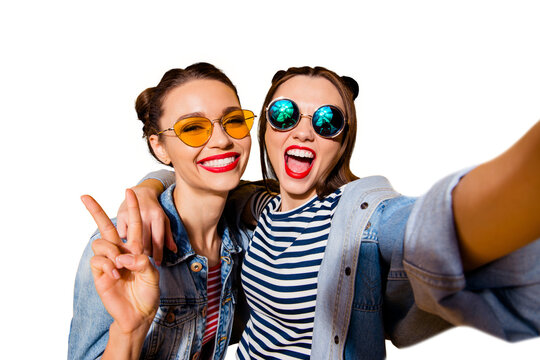 Two glad positive grinning lady stand in glasses spectacles street style stylish trendy cool casual denim jeans clothes isolated on yellow background in take picture on cellular make hollywood smile