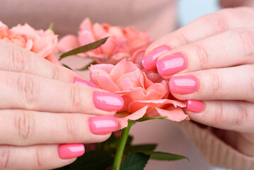 The woman's hands are touching the delicate pink petals of the rosebud.