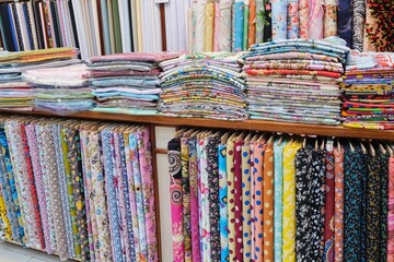 Retail display place of fabric and textile stacked on shelves in fabric store. Multi different colors and patterns on the textile shop. 