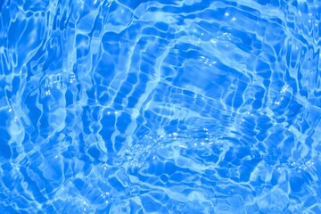 Light blue water with sun reflections. Closeup, selective focus, defocus