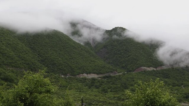 Gudauri, Georgia mountains in cloudy weather with green grass and snow on  pics in May. 