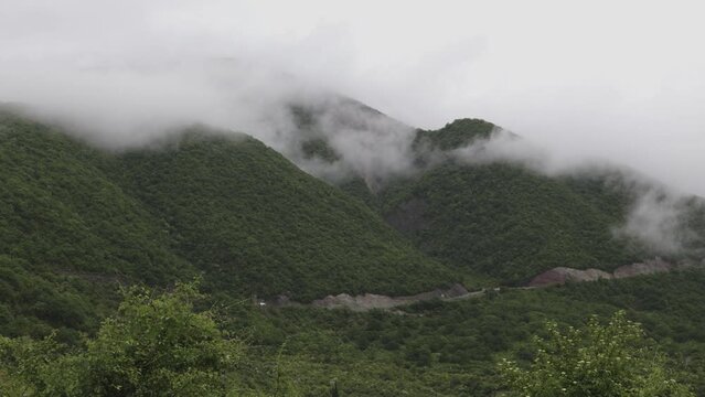 Gudauri, Georgia mountains in cloudy weather with green grass and snow on  pics in May. 