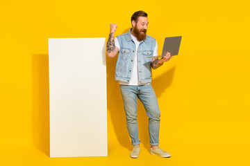 Photo of cool lucky guy dressed denim vest working modern gadget empty space isolated yellow color background