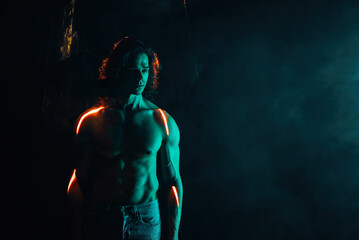 Sporty handsome muscular man portrait under smoke illumination, laser light
