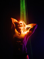 Sporty handsome muscular man portrait under colorful illumination, laser light