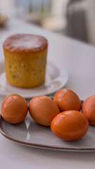 Boiled brown eggs in a gray plate on a background of a kulich. Easter concept.