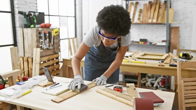 A focused woman sands wood in a well-equipped carpentry workshop, showcasing her skill and dedication to the craft.