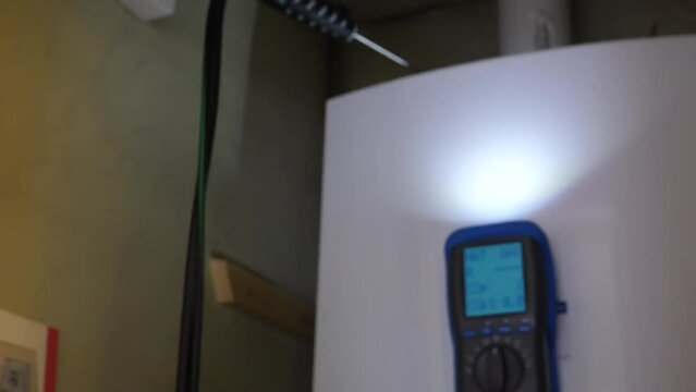 Engineer fingers pressing flue gas analyser tester buttons, performing domestic water and heating boiler combustion fumes CO carbon monoxide check, blurred view, handheld shot.