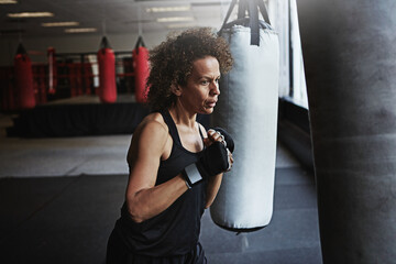 Gym, punching bag and mature woman in boxing for workout, challenge or competition training. Power,...