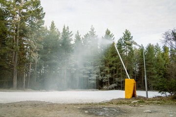 Snow lance or snow gun makes artificial snow in the middle of a forest near a ski resort