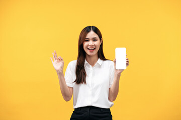 Young asian woman wearing white short sleeve shirt and smiling while holding smartphone with blank...