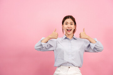 Young asian woman using both hands with fingers to thumbs up gesture with surprised and excited face