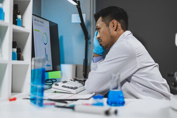 A scientist working in a laboratory is stressed out analyzing the results of an experiment on a...