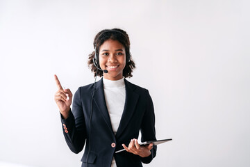 A woman in a business suit is smiling and pointing to a tablet