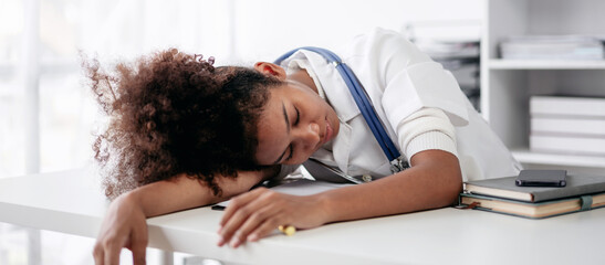 A young woman in a white coat is sleeping on a desk