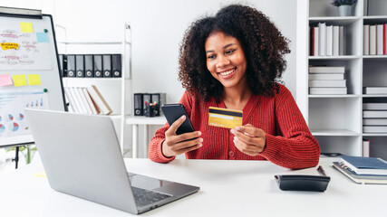 A woman is smiling while using her cell phone to pay for something