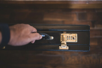 Top view of briefcase with blurred hand of young man holding de handle.