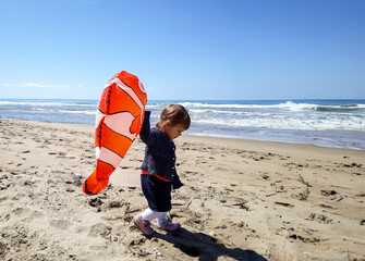 Little girl finds a lost balloon on the beach, a poignant symbol of ocean drift.This candid moment captures both childhood curiosity and the unintended consequences of plastic pollution.