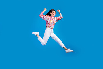 Full length photo of funky cheerful lady dressed print blouse rising fist jumping high running...
