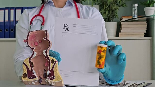 Doctor model of the rectum with inflamed vascular structures and pills. Problem of hemorrhoids and treatment of constipation