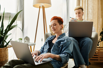 Two women with short hair, an LGBT couple, focused on laptops in a stylish living room setting.