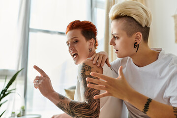 Two women with tattoos engage in a heated argument in a stylish living room. Short hair, LGBT...