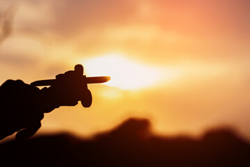 Silhouette of hand holding airplane in nature at sunset. The pilot is that dream in the future of...