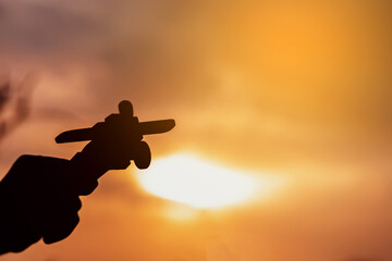 Silhouette of hand holding airplane in nature at sunset. The pilot is that dream in the future of the boy. Copy space.