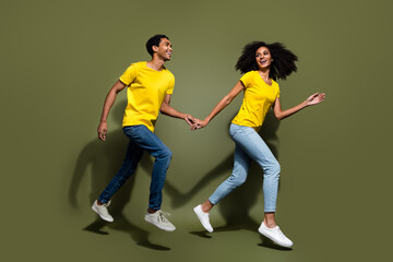 Full body portrait of two nice people hold arms run jump wear t-shirt isolated on khaki color background