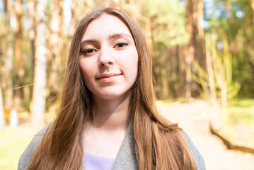 Portrait of a beautiful teenage girl, young woman with long hair in the park