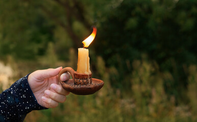 candlestick with burning candle in woman hand outdoor, abstract natural background. magic,...