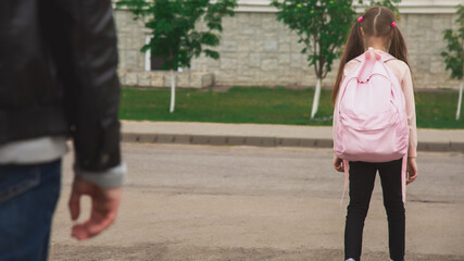 Father with cute little daughter see off to school elementary class outdoor near school building. Child pupil with backpack going dad with love before going classroom