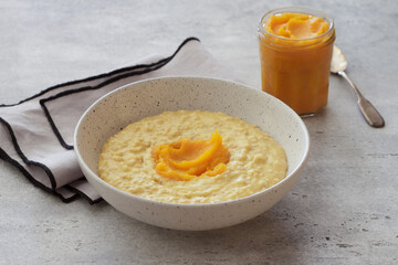 Bowl of oatmeal with pumpkin on a gray textured background. Delicious healthy homemade breakfast