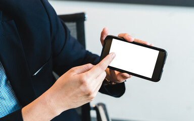 Businessman holding blank screen smartphone in modern office. Showing screen to audiences. Mock up of a man holding device and touching screen.