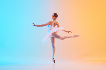 Young ballerina in white tutu doing arabesque in motion in neon light against blue-orange gradient background. Concept of art, movement, grace, classical and modern fusion, beauty and fashion. Ad