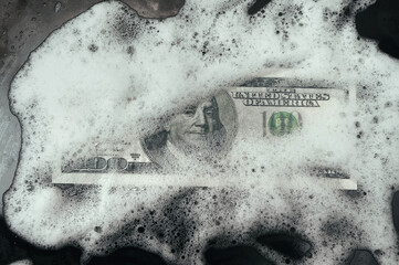 100 dollar bill lies in foam on a baking sheet. View from above. Concept of money laundering,...