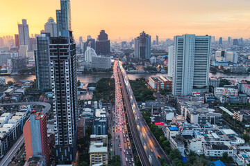 Obraz premium Cityscape of sunrise sky over office building and car traffic on the bridge at Bangkok