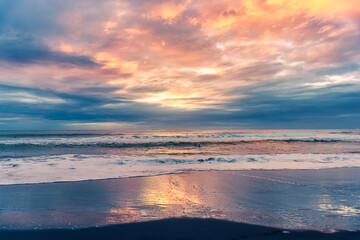Colorful sunset sky over Tasman sea at Piha beach, New Zealand