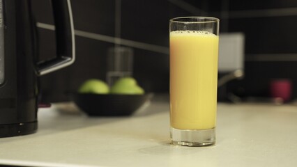 Male hand taking glass with fresh fruit juice at kitchen at home. Slow motion