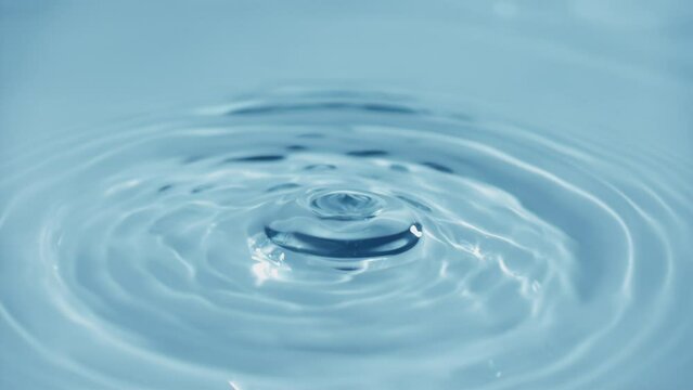 Natural mineral water splashing. Crystal clear drop of cosmetic essence serum falling in slow motion. Body moisturizing cosmetics formulating. Commercial beauty product blue liquid abstract background