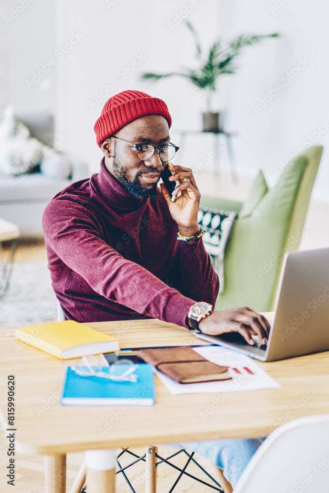 Poster pensive african american man installing application on netbook talking on mobile phone with operator