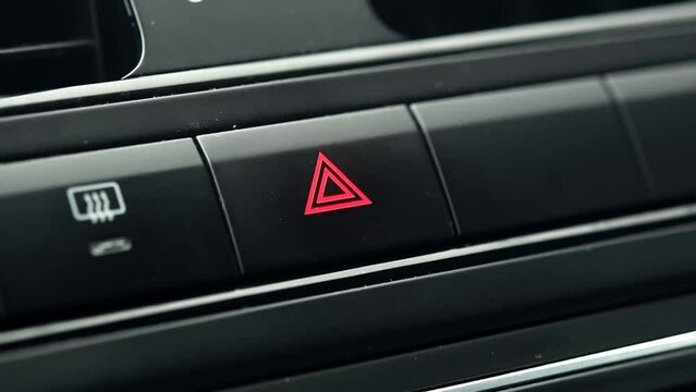 Person turns on a car's hazard warning flasher button, close-up.
